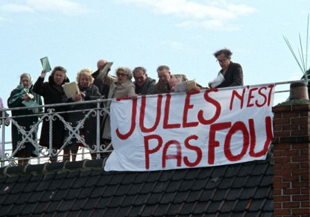 Menschen stehen auf einem Dach und halten ein Banner mit französischem Schriftzug nach unten.