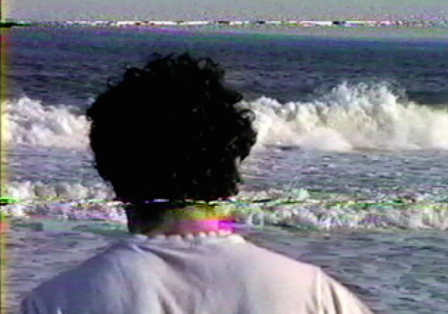 R&uuml;ckenansicht einer Person am Meer die auf Wellen schaut.