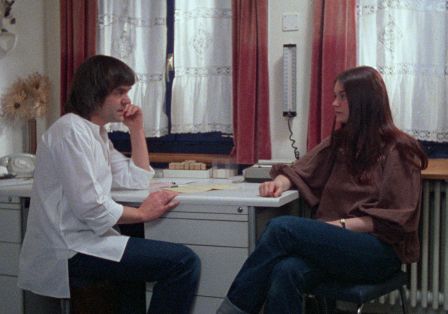 Eine Frau sitzt einem Arzt in einem Praxiszimmer gegenüber und sie sprechen miteinander.