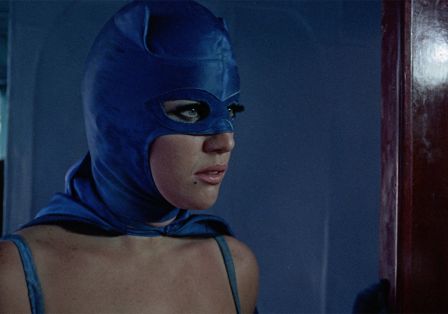 Eine Frau mit langen Wimpern in einer blauen Kostümmaske blickt zur Seite.