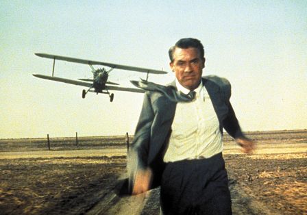 Cary Grant rennt vor einem Propellerflugzeug davon.