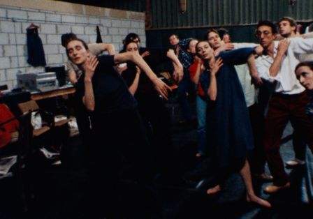 Mehrere Menschen stehen synchron in einer Tanzposition.