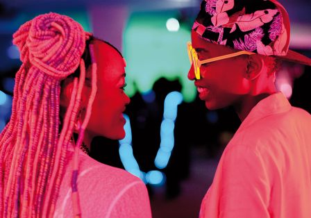 Zwei Personen, die sich ansehen, in pinkem Licht.