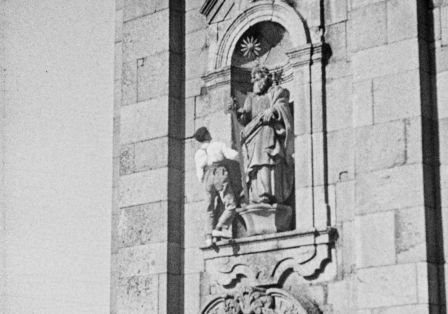 Ein Mann steht in einer Fassadeneinkerbung mit einer Statue.