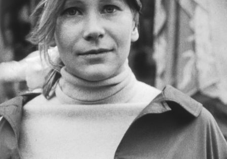 Eine junge Frau mit hellem Haar und hellen Augen blickt leicht lächelnd in die Kamera.