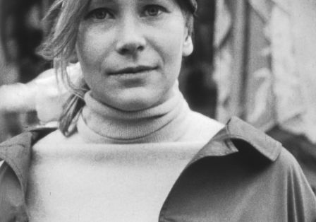 Eine junge Frau mit hellem Haar und hellen Augen blickt leicht lächelnd in die Kamera.