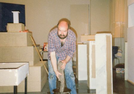 Ein Mann, Wolfgang Theis, steht in einem Museumsraum und wringt einen Mob aus.