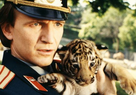 Ein Mann in Uniform h&auml;lt ein Tigerbaby.