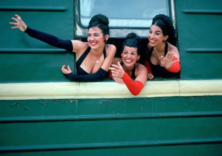 Drei Frauen lachen aus einem Zugfenster.