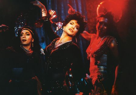 Drei Drag Queens in glitzernden Kost&uuml;men tanzen auf einer B&uuml;hne.