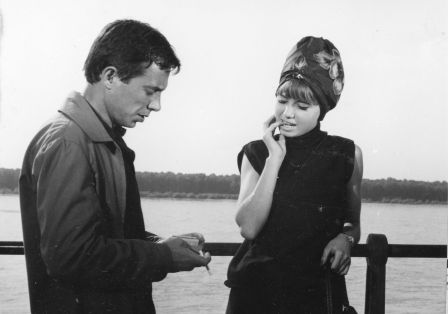 Ein schwarz wei&szlig; Bild aus den 80ern. Ein Mann und eine Frau stehen auf einem Steg vor einem See. Der Mann holt eine Zigarette raus.