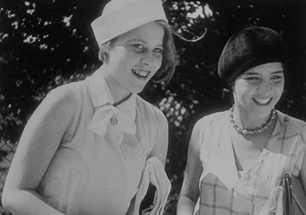 Zwei junge Frauen in schwarz-weißen Sommeroutfits aus den 1930er-Jahren lächeln fröhlich.