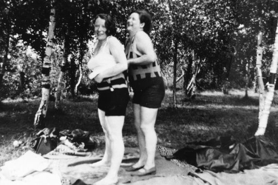 Zwei &auml;ltere Frauen in Badeanzug stehen im Wald und lachen.