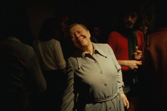 Die Schauspielerin Brigitte Mira schließt mit einem freudestrahlenden Lächeln die Augen und wird dabei von sanftem Licht erleuchtet.