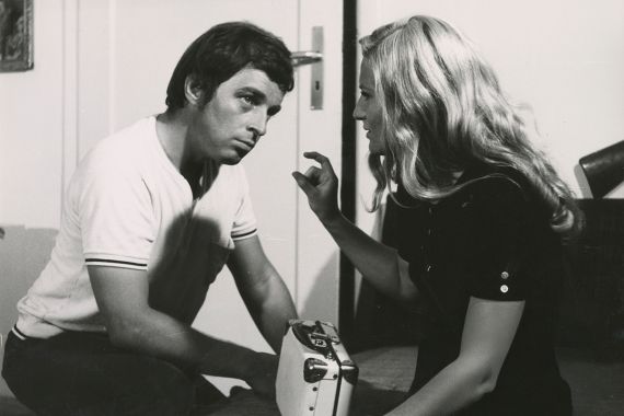 Ein Mann h&ouml;rt einer Frau zu, die mit Daumen und Zeigefinger etwas Kleines anzeigt.