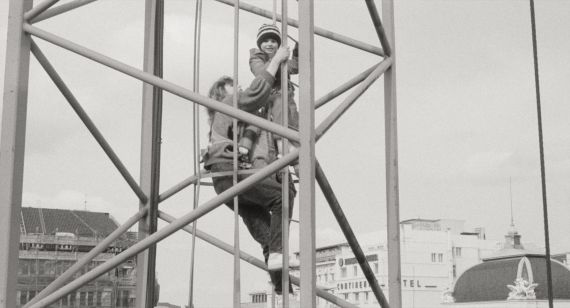 Eine Frau und ein Kleinkind klettern einen Kran hoch.