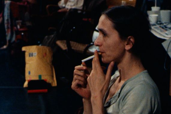 Pina Bausch, a woman with her hair tied in a ponytail, lights a cigarette.