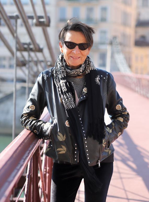 Die Regisseurin Monika Treut posiert mit Sonnenbrille auf einer Br&uuml;cke.
