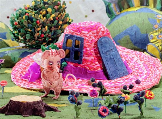 Eine rosafarbene Maus steht vor einem pinken Sommerhut, der zu einem Haus umfunktioniert wurde.