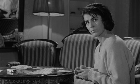 Eine Frau an einem Tisch  mit Spielkarten schaut mit ernstem Blick auf.