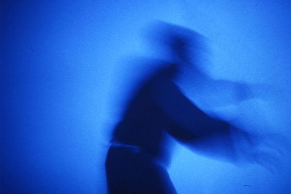 Man sieht einen Schatten einer Gestalt auf blauem Hintergrund.