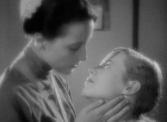 Schwarz-wei&szlig;-Szene: Zwei junge Frauen lehnen ihre Gesichter zueinander als wollten sie sich k&uuml;ssen..