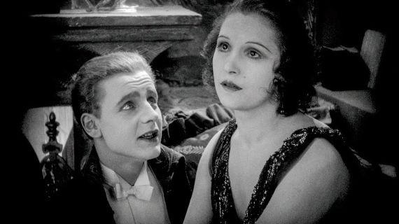 Schwarz-wei&szlig;e Filmszene eines Gespr&auml;chs von Mann und Frau. Dabei spricht der Mann und die Frau starrt in die Leere.