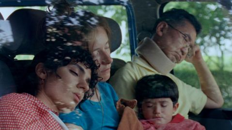 Drei Erwachsene und ein Kind sitzen schlafend in einem Auto.