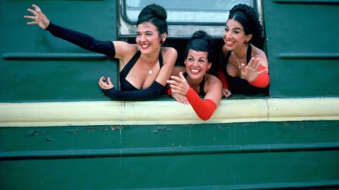 Drei Frauen lachen aus einem Zugfenster.