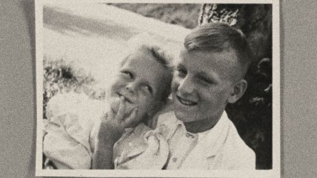 Ein l&auml;chelndes M&auml;dchen und ein zwinkernder Junge sind auf einem Foto zu sehen, das auf einem Tisch liegt.