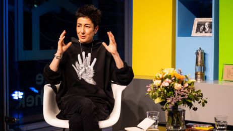 Die Moderatorin Dunja Hayali sitzt als Gast im Studio des Fernsehsalons neben einem Blumenstrauß und gestikuliert sprechend mit den Händen.