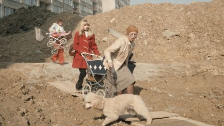 Drei Frauen mit zwei Kinderw&auml;gen laufen &uuml;ber einen riesiegen Schuttberg in der Stadt.