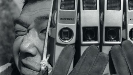 Ein Mann h&auml;lt mehrere Kameras vor sein Gesicht.