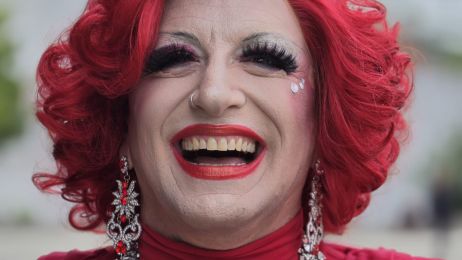 Portrait einer Drag-Queen mit rotem Haar und rotem Kleid.