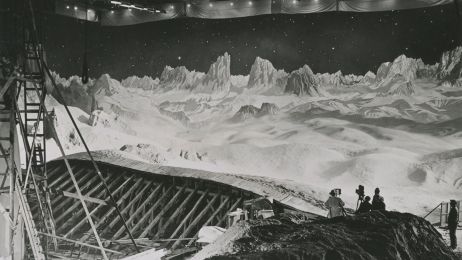 Ein schwarz-weißes Bild zeigt in einem alten Filmstudio eine Crew, die eine Mondlandschaft filmt.