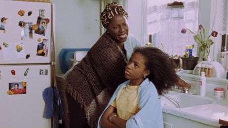 Eine Frau schaut ver&auml;rgert auf ein M&auml;dchen, das genervt vor einem Waschbecken sitzt, mit offenem Haar und einem Handtuch auf den Schultern.