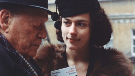 Eine junge Frau schat einen &auml;lteren Mann freundlich an. Sie h&auml;lt ein Buch: Lotte in Weimar von Thomas Mann