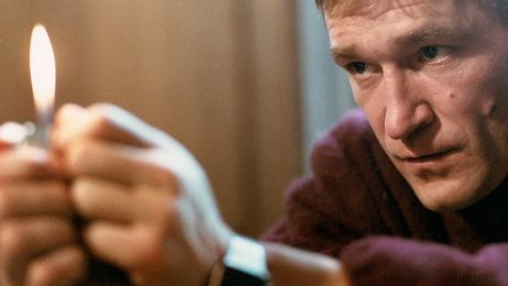 Ein Mann h&auml;lt ein Feuerzeug in den H&auml;nden und schaut auf die Flamme.