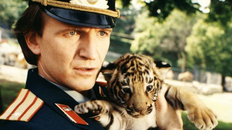 Ein Mann in Uniform h&auml;lt ein Tigerbaby.