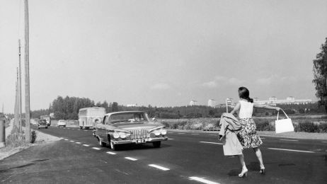 Schwarz-wei&szlig;-Foto einer Frau, die sich auf der Stra&szlig;e vor ein Auto stellt. 