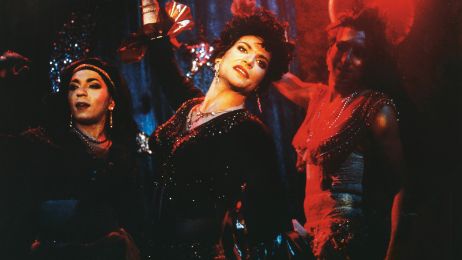 Drei Drag Queens in glitzernden Kost&uuml;men tanzen auf einer B&uuml;hne.