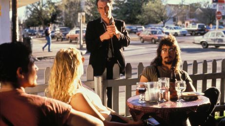 Junge Menschen sitzen im Caf&eacute; an einem Tisch im Freien und unterhalten sich.