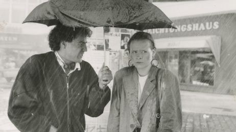 Zwei Personen stehen unter einem Regenschirm und unterhalten sich.