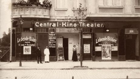 Drei Personen und ein Hund vor einer Kinofassade in Berlin, Schwarzwei&szlig;aufnahme aus dem Jahr 1910.