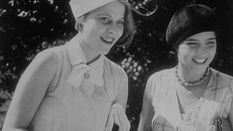 Zwei junge Frauen in schwarz-weißen Sommeroutfits aus den 1930er-Jahren lächeln fröhlich.